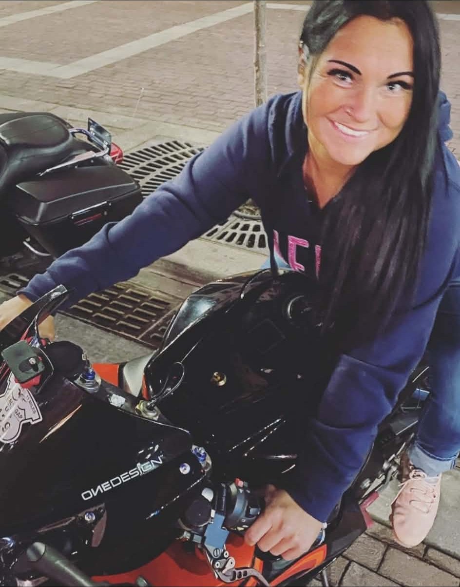 Mandy, mobile bartender and karaoke host, smiling on her motorcycle